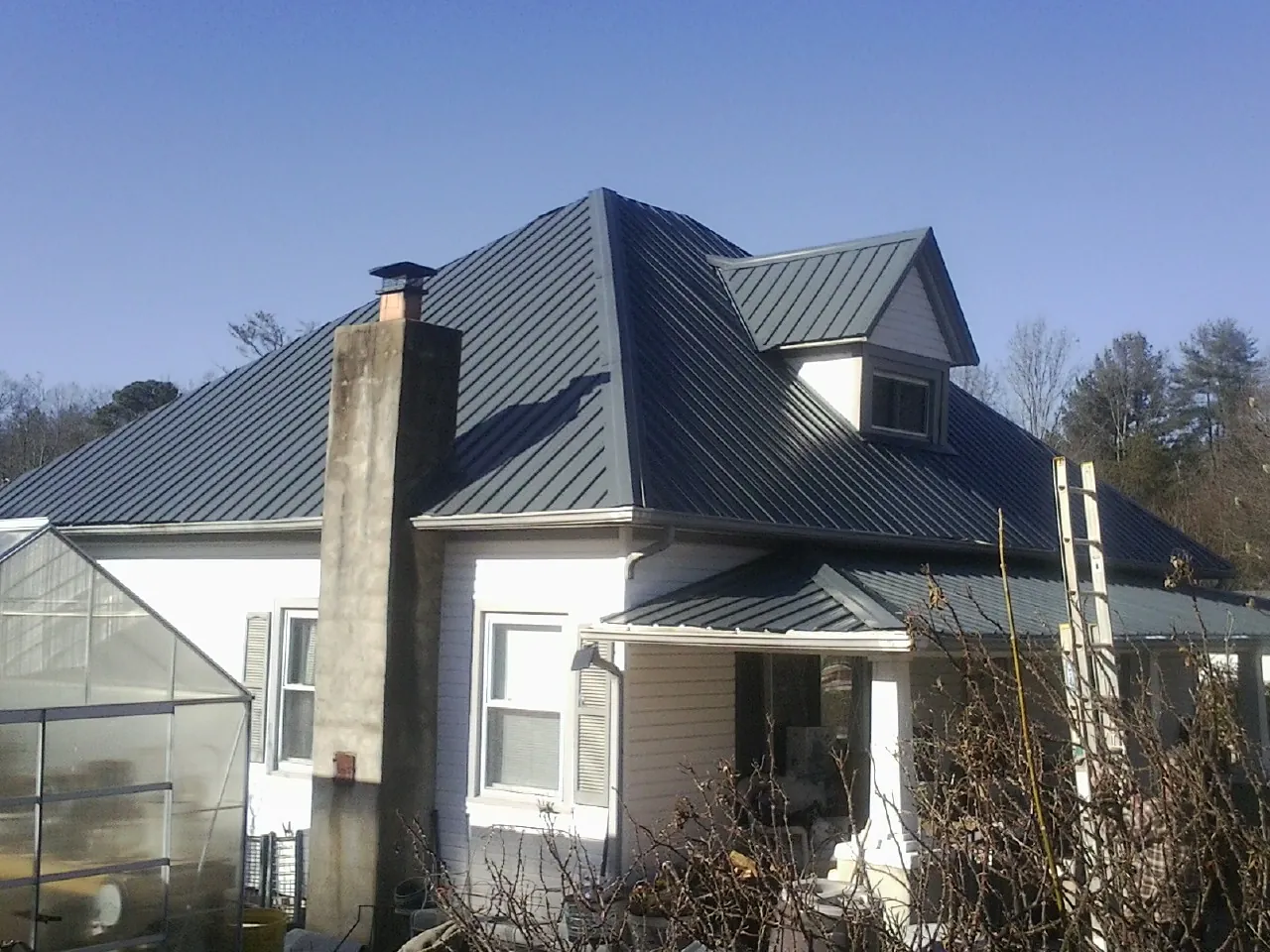 Dark blue standing seam metal roof on a white farmhouse with dormer — Slate & Tile Roof Repair by Roofing Brothers in Kooskia