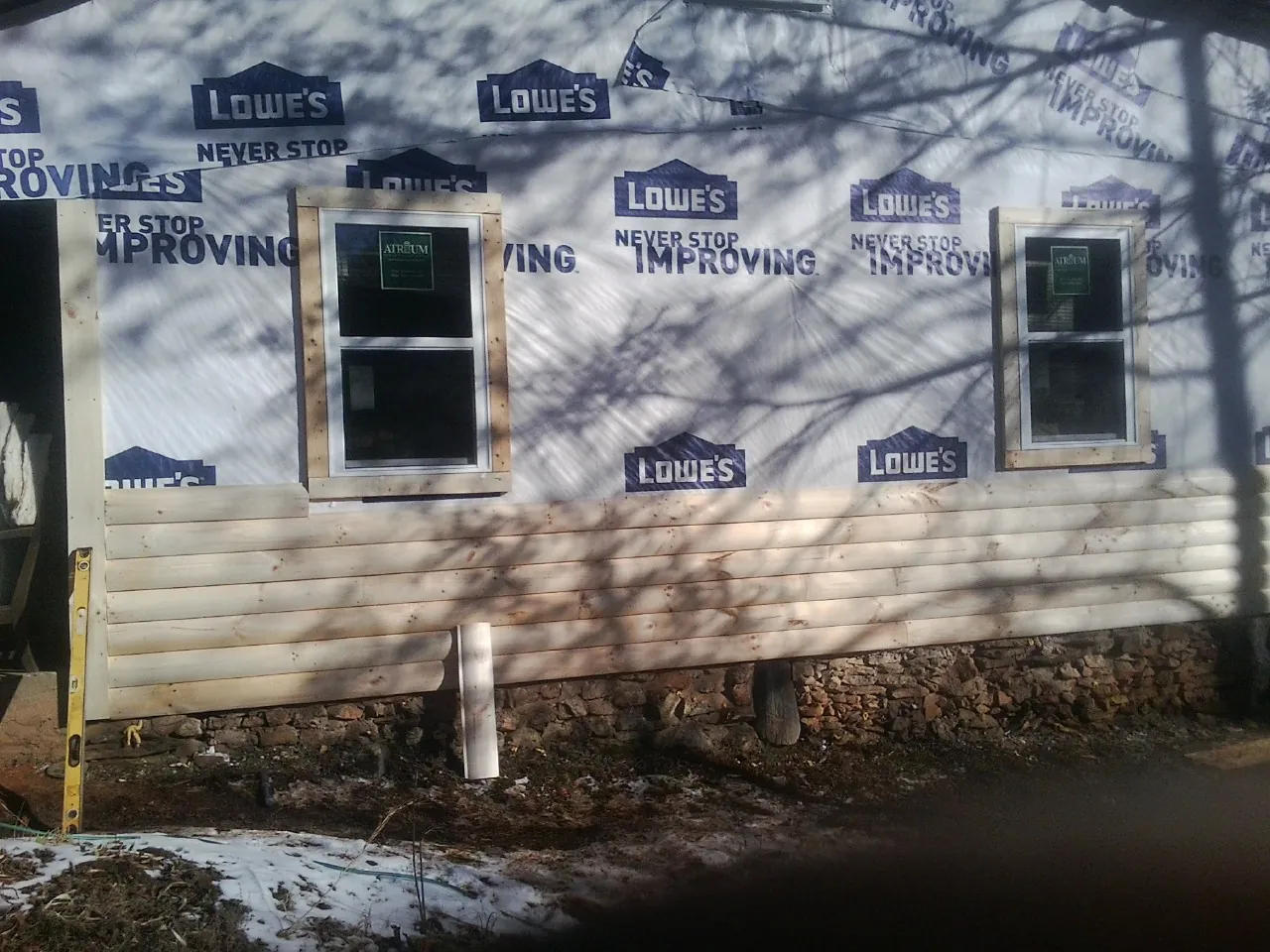 House wrap and new log siding going up on an exterior wall in Kooskia