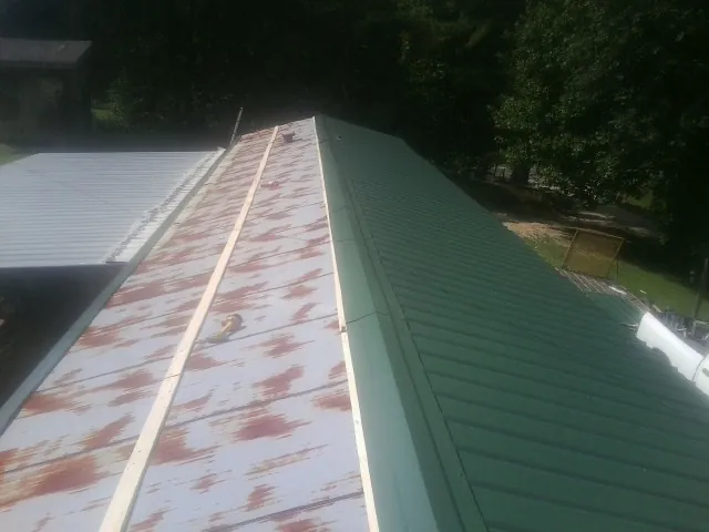 Old rusted panels beside newly installed green metal roofing — Wind Damage Roof Repair by Roofing Brothers in Kooskia