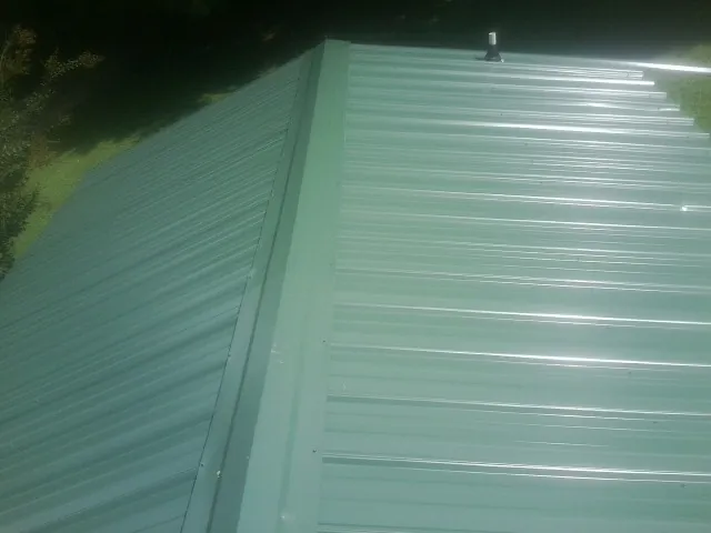New green metal panels meeting at the ridge of a roof — Flat Roof Repair work by our crew in Kooskia