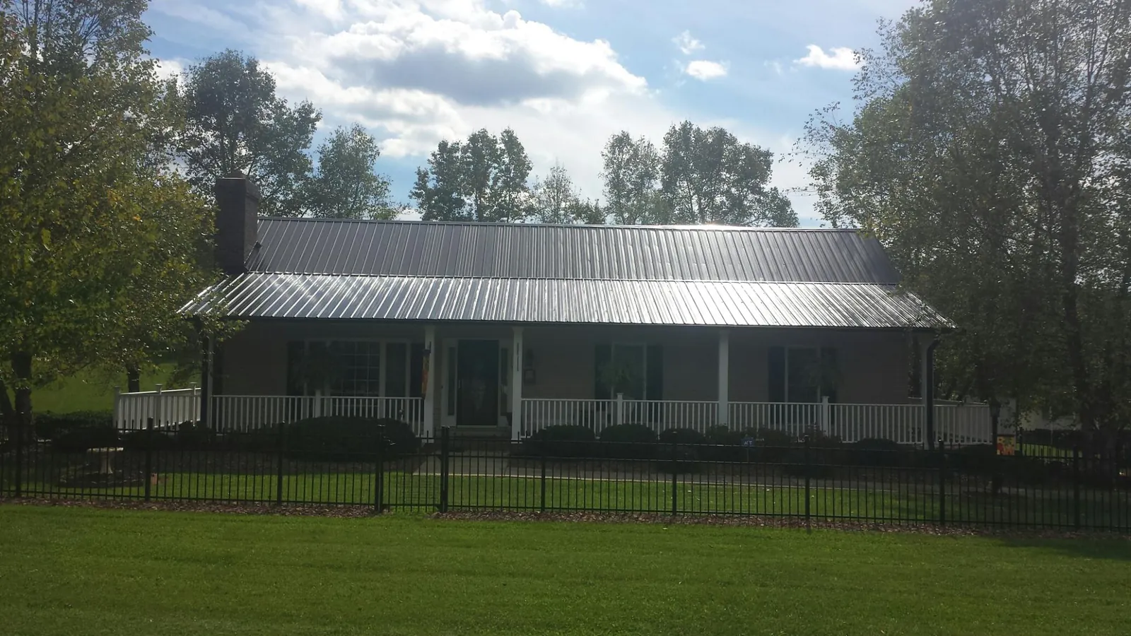 Gray metal roof on a brick ranch with a full width front porch — Gutter Guard Installation work by our crew in Kooskia