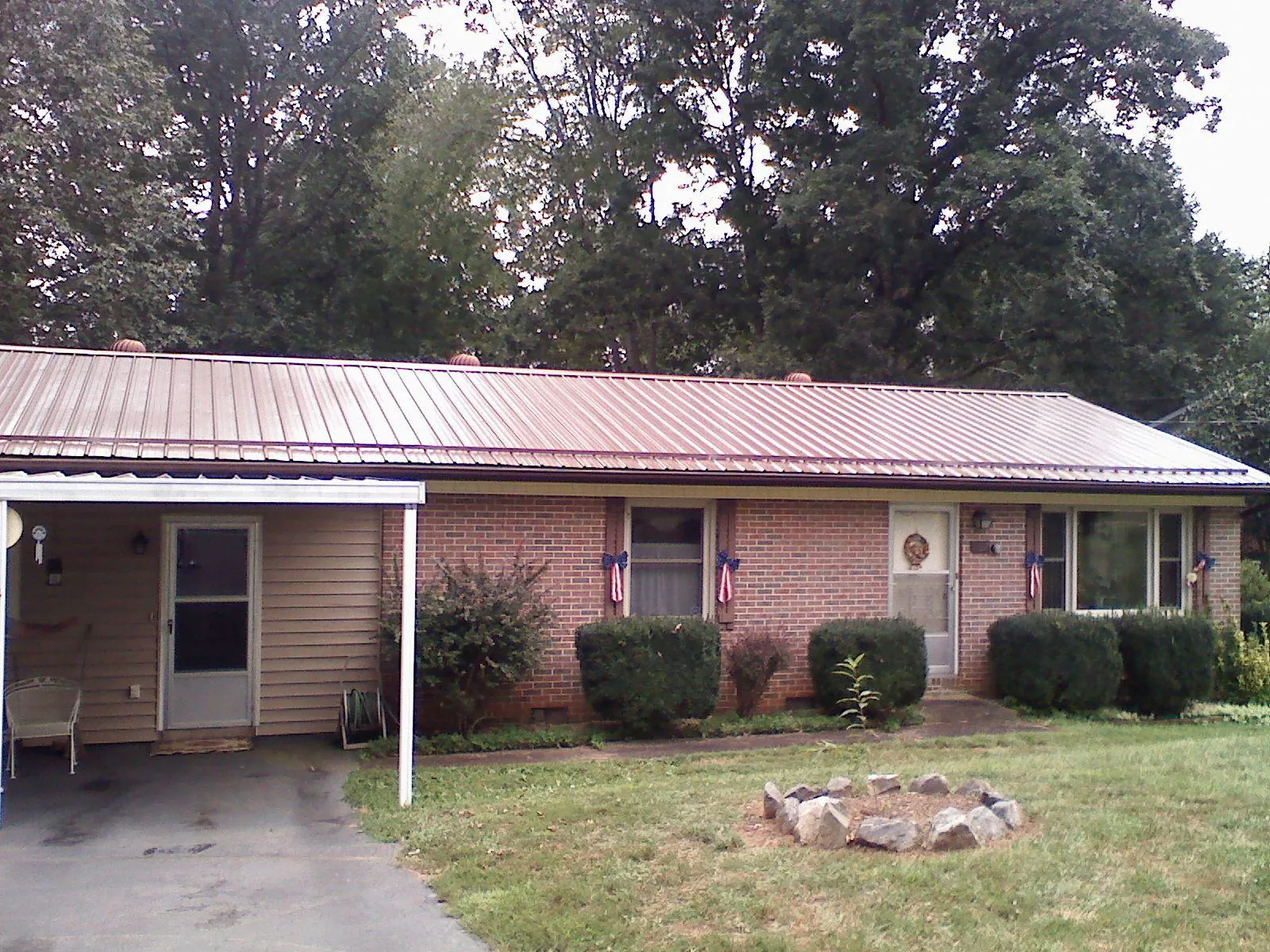 Bronze metal roof and carport on a brick ranch home — Roof Repair work by our crew in Kooskia