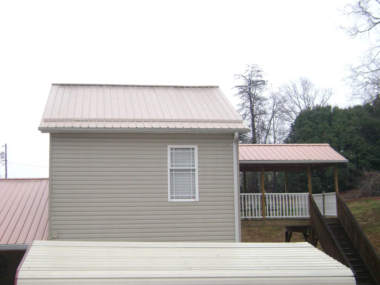 Tan metal roofs on a two story addition and attached porch, from a Roof Replacement job in Kooskia