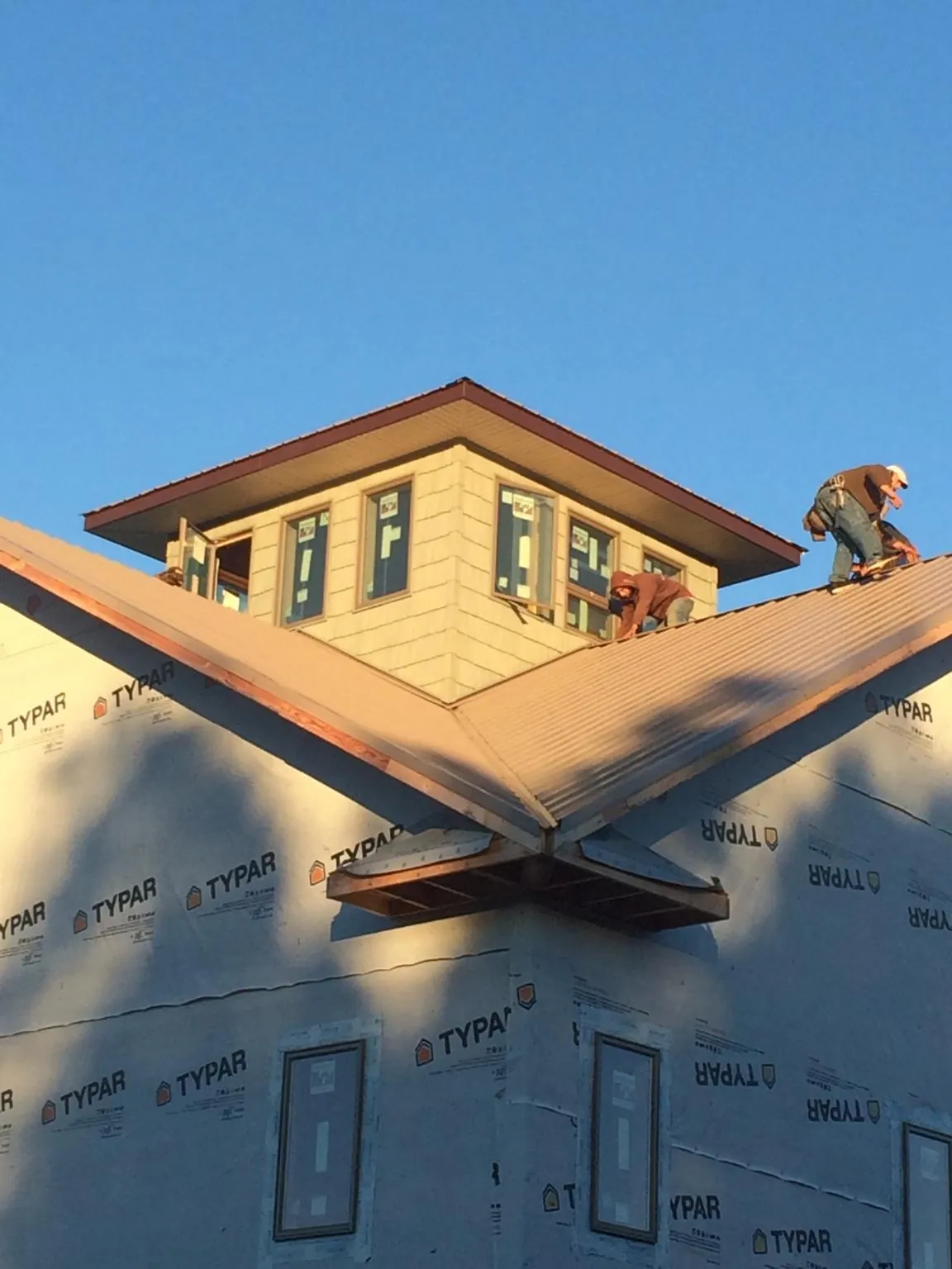 Roofers working around a rooftop cupola on a new metal roof at sunset — Roof Waterproofing in Kooskia by Roofing Brothers